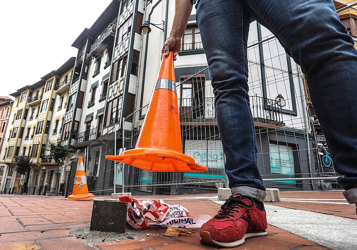Un joven levanta uno de los conos que oculta uno de los tres bolardos que fue cortado.