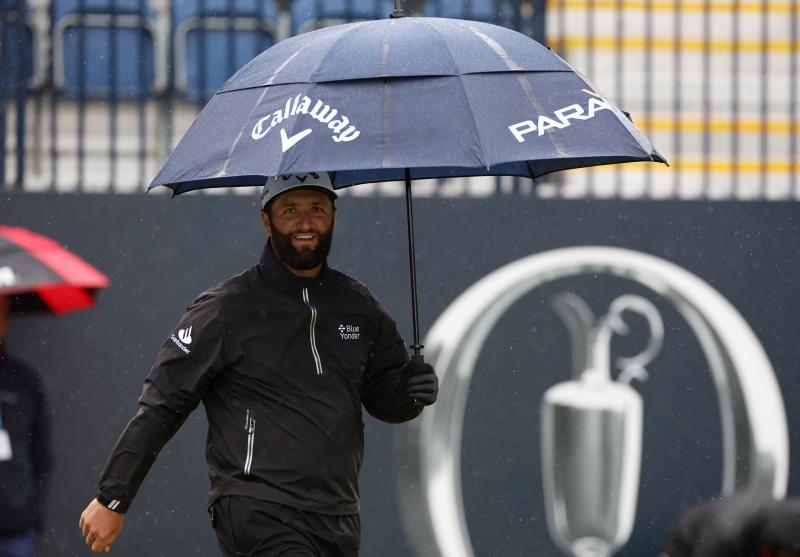 Rahm se protege con un paraguas durante el entrenamiento en el Royal Liverpool Golf Club.