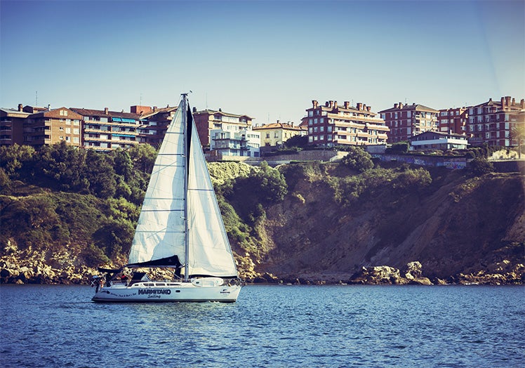 El velero de Marmitako Sailing zarpa de Getxo, con La Galea al fondo.