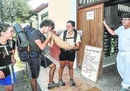 Mariona Cervero, Roger Bonet y Anna Pontes, que están conociendo Euskadi a pie, prueban el pan de Richard Alpire en la bajada de Arrieta a Fruiz.