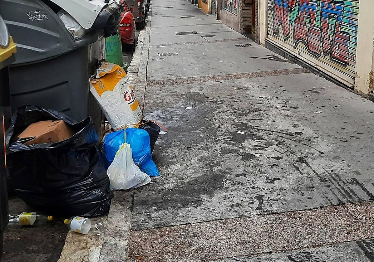 La basura se amontona en el exterior de un contenedor de la calle Benito Guinea