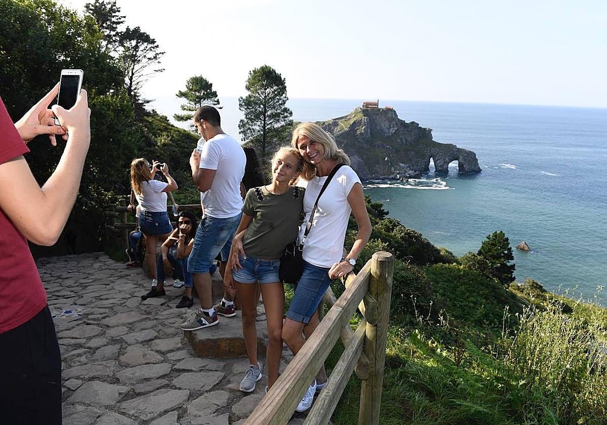 Turista talde bat argazkiak ateratzen San Juan de Gaztelugatxeren aurrean