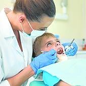 Una odontóloga examina el estado de los dientes de un niño.