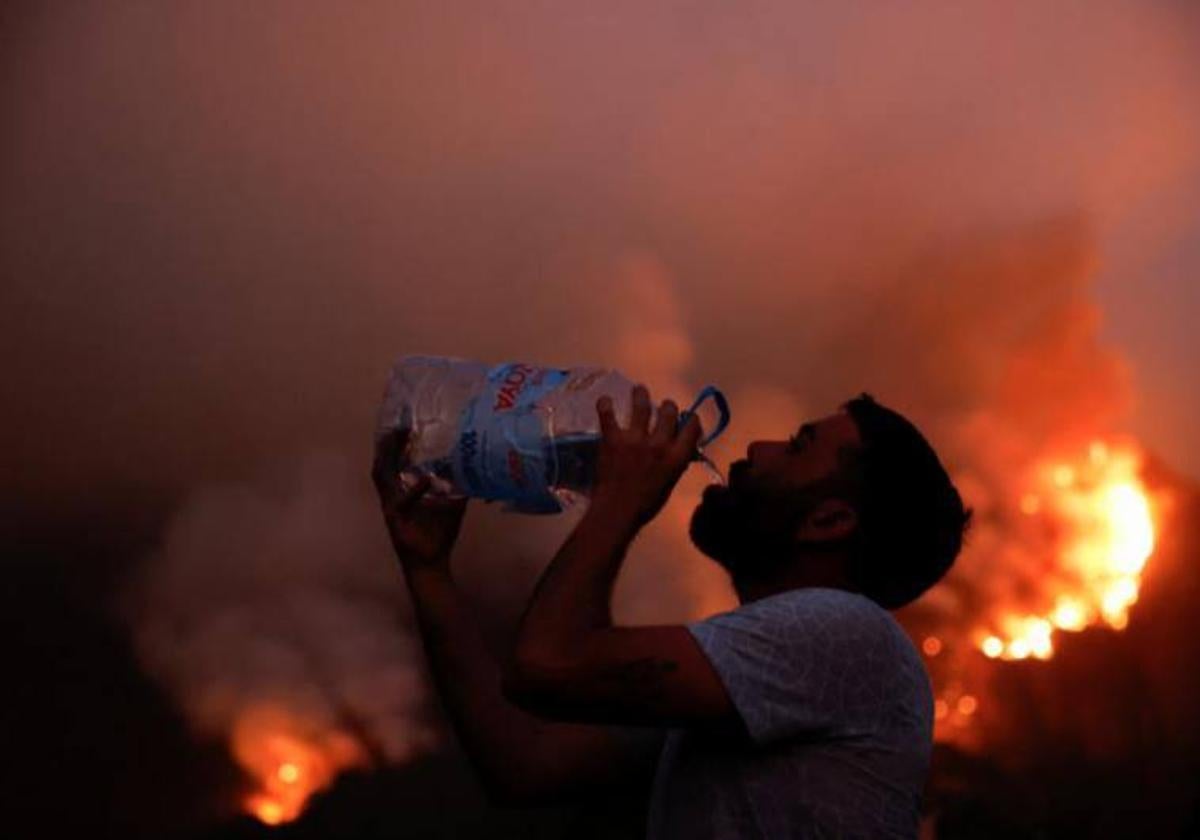 Un vecino de Aguamansa bebe agua frente a uno de los frentes activos del incendio.