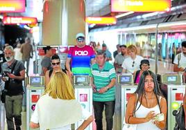 Viajeros pasan por la canceladora en la estación de metro de Las Arenas.