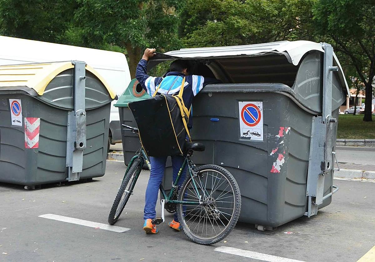 Una persona ajena a la información busca en un contenedor.