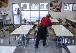 Una trabajadora de la cafetería de Santiago coloca unas mesas