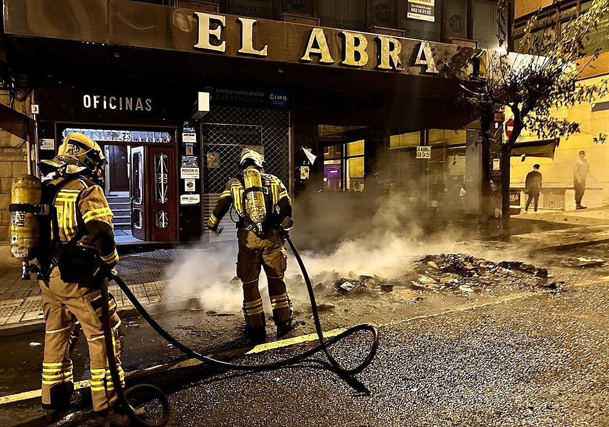 Dos bomberos sofocan el incendio que calcinó dos contenedores.
