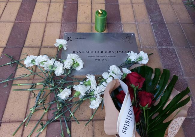 La placa, con una vela en su recuerdo, tras la ofrenda floral.