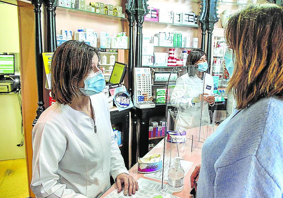 Dos farmacéuticas atienden a una clienta.