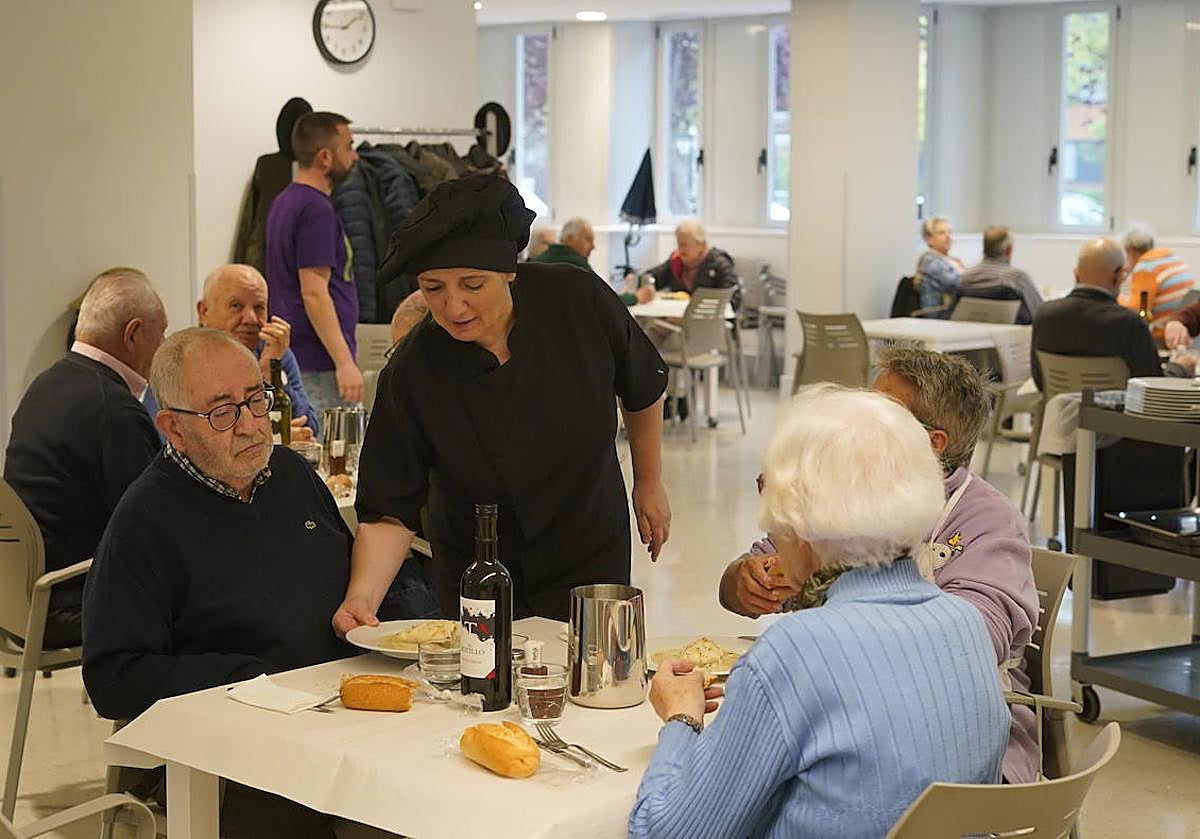 Una trabajadora sirve platos de bacalao, segundo en el menú de ayer, a los usuarios del comedor del centro Bizan de San Martín.