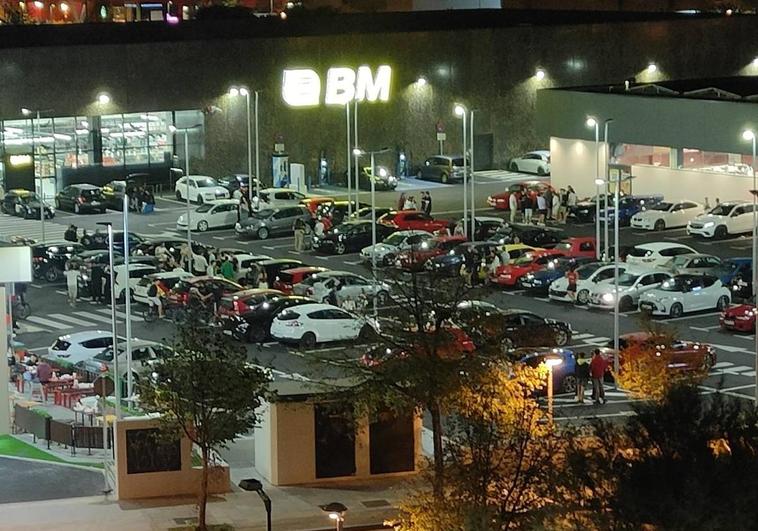 Varios grupos de personas beben y comen en el parking del nuevo centro comercial de Salburua.