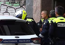 Agentes locales introducen en un coche patrulla a uno de los ladrones interceptados en el piso de Coronación.