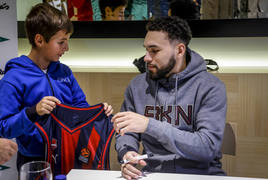 Chris Chiozza se dispone a estampar su firma en la camiseta de un joven seguidor baskonista.