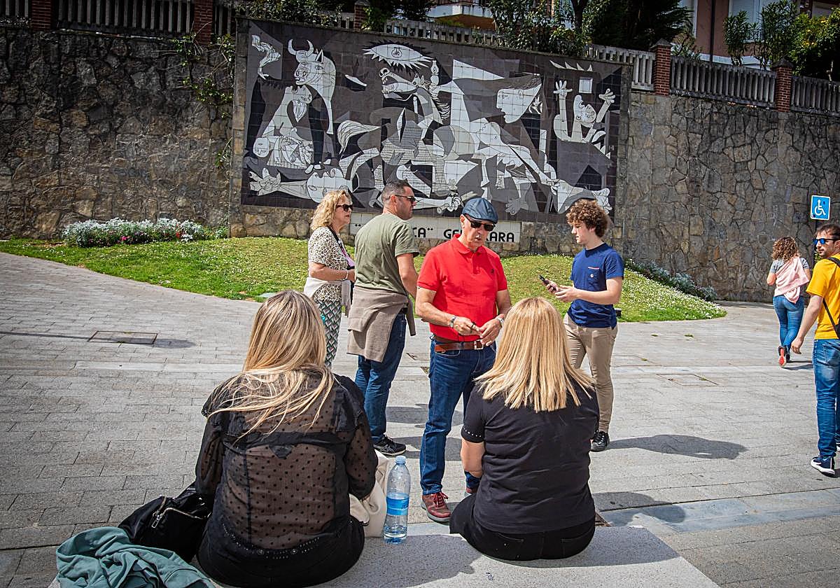 Turistas frente a la réplica en baldosa del cuadro 'Guernica' de Picasso.