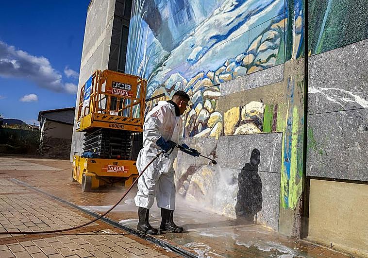 Un operario elimina las pinturas de la fachada del edificio.