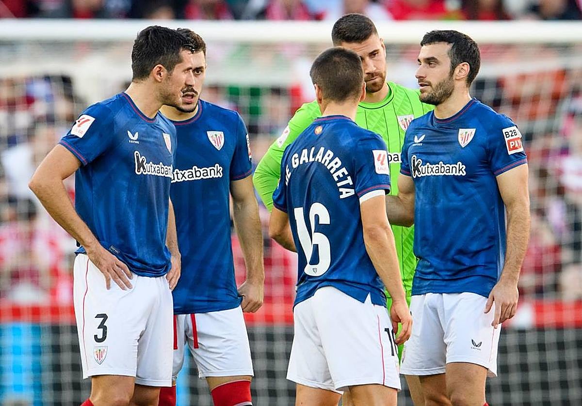 Los jugadores rojiblancos conversan en el césped con el partido suspendido.