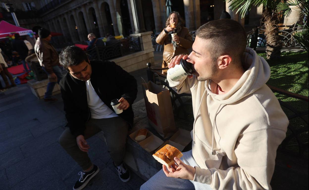 Grupos de gente comiendo sus porciones en la Plaza Nueva. 