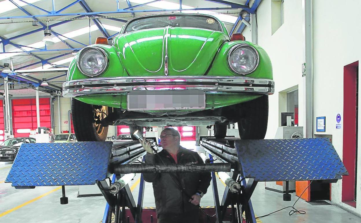 Un mecánico supervisa los bajos de un coche, durante la Inspección Técnica de Vehículos (ITV). 