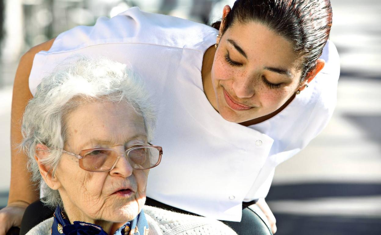 Una anciana es atendida por una cuidadora 