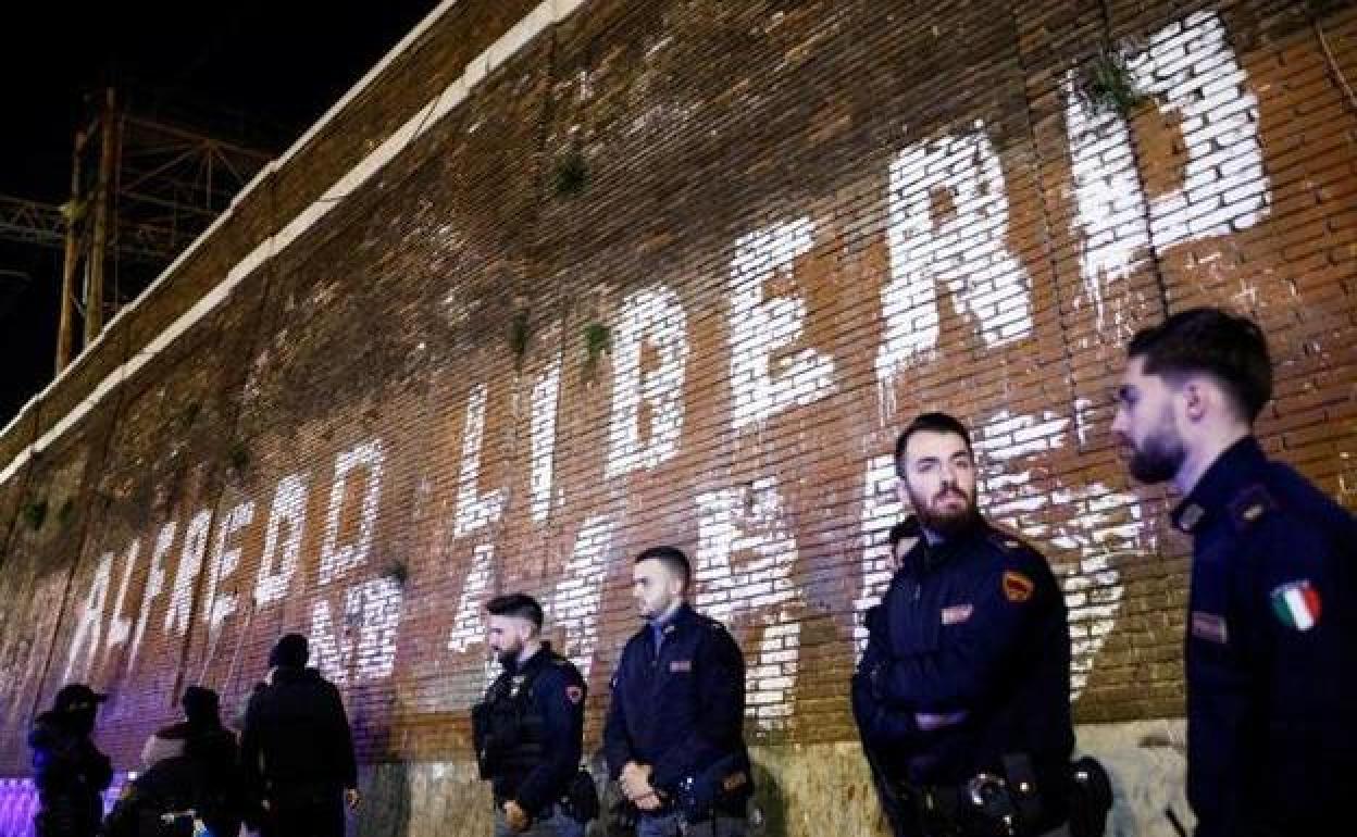 Policías italianos montan guardia junto a un muro en el que se observa una pintada en favor de la puesta en libertad del anarquista Alfredo Cospito.