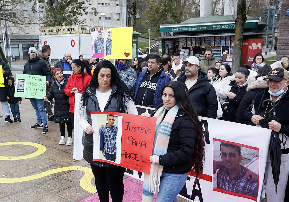 Maite, prima de Ángel, y Zaira, su hermana, posan junto a una pancarta que clama justicia.