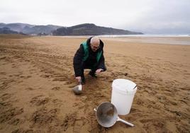 Un operario busca pellets en la playa de La Arena.