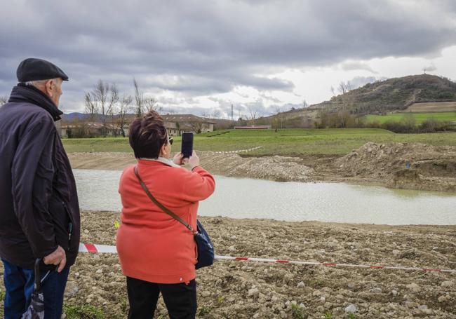 Una pareja de jubilados fotografía la recién creada balsa de anfibios junto al anfiteatro natural.