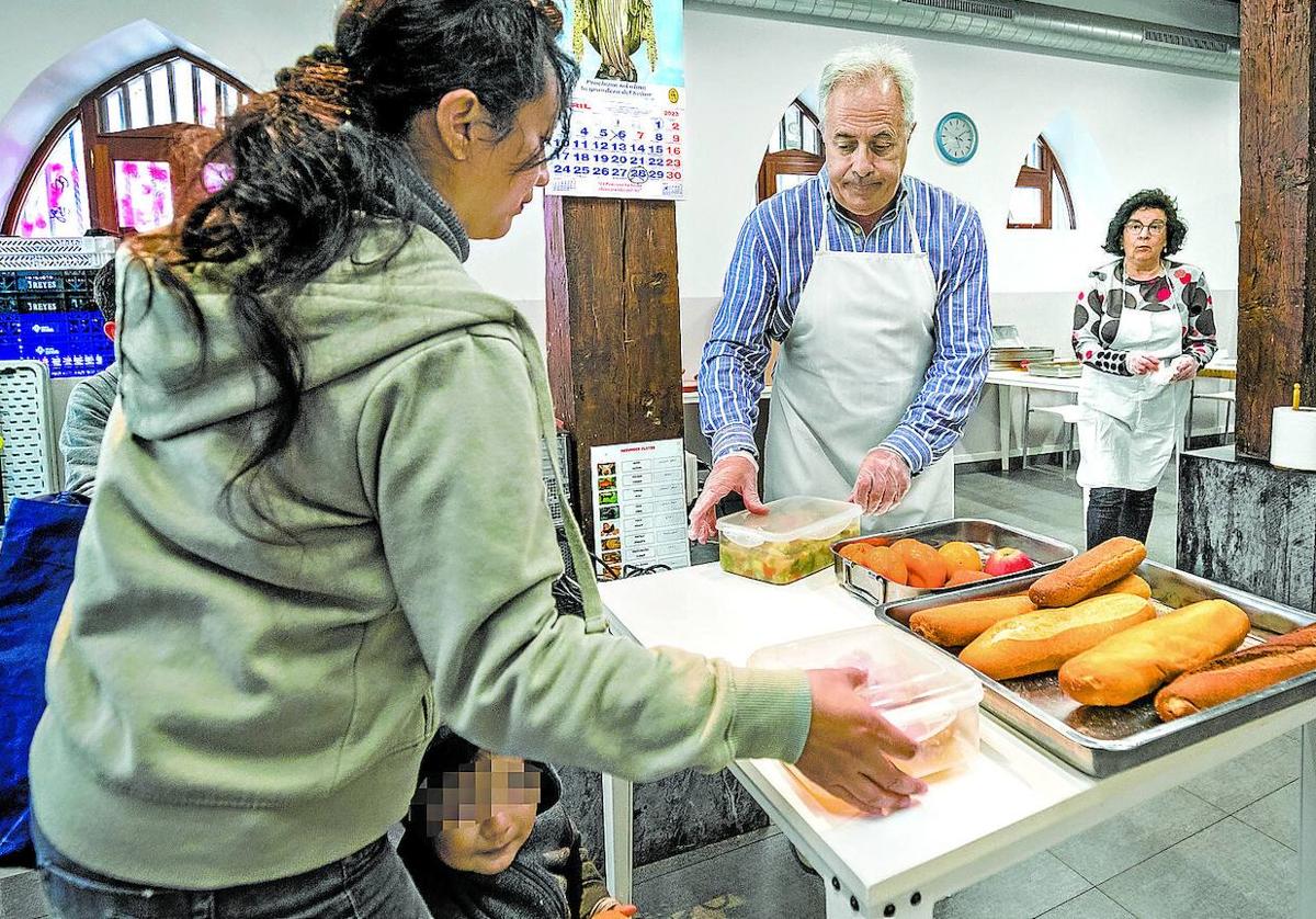 Una mujer con su niña recoge un menú en el comedor de Berakah, obra social ligada a la Diócesis.