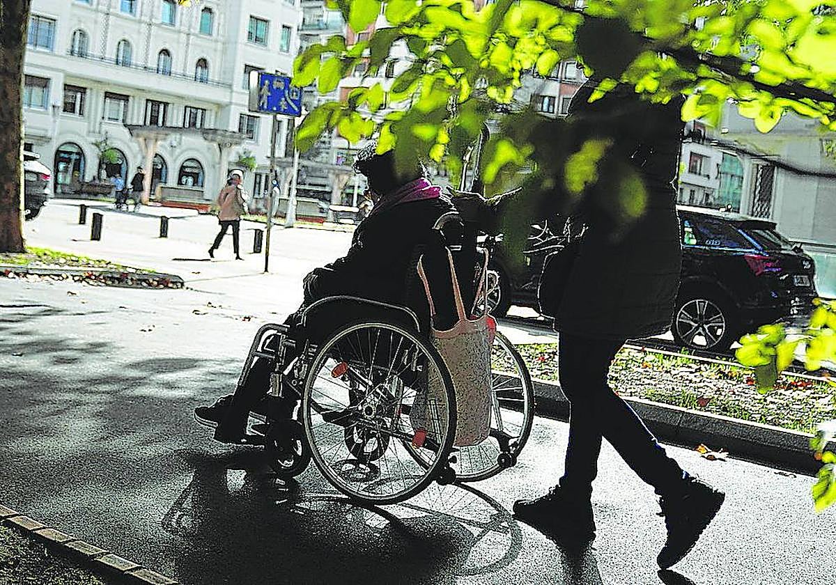 Un cuidador pasea a una persona dependiente en Bilbao.