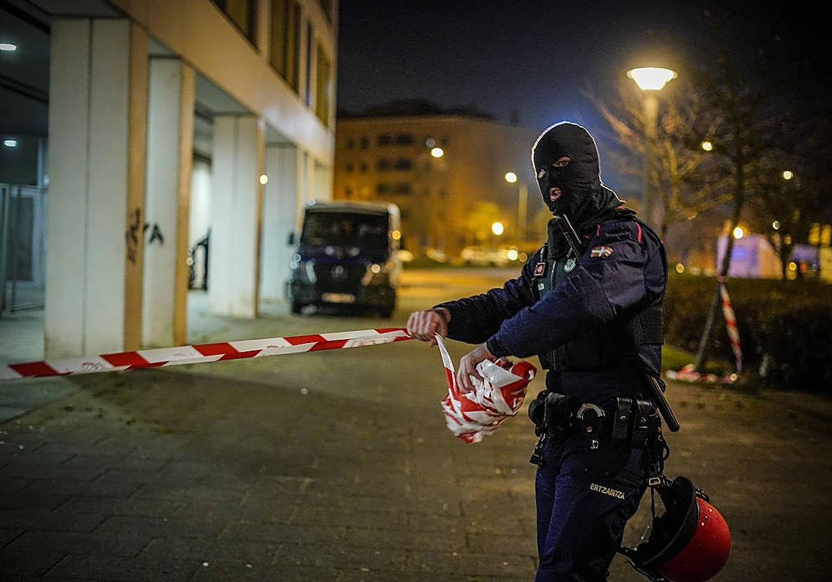 Un ertzaina retira la cinta de seguridad tras finalizar el operativo en la calle Helsinki.