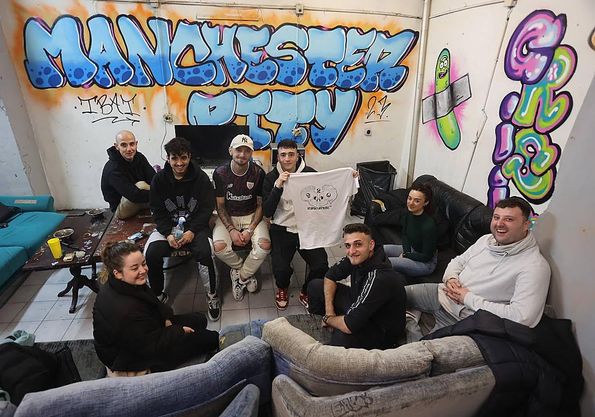 Gaizka Carnero, con la camiseta de PuntoNorte920 en las manos, y varios miembros más de su cuadrilla en la lonja de Portugalete.