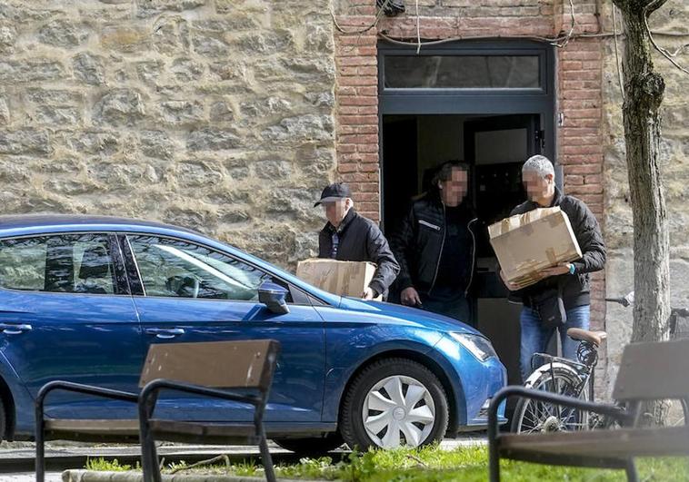 Ertzainas sacan material incautado de uno de los pisos registrados este jueves.