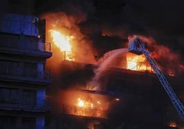 Un bombero echa agua pulverizada sobre la fachada del edificio.