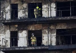 Dos bomberos revisan una de las fachadas quemadas, este lunes.