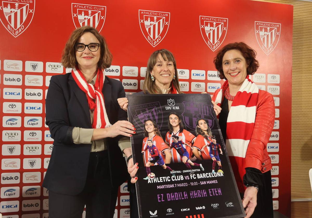 La diputada general de Bizkaia, Elixabete Etxanobe; la vicepresidenta del Athletic, Nerea Ortiz; y la alcaldesa de Bilbao, Amaia Arregi, con el cartel del partido.