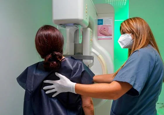 Una sanitaria ayuda a la paciente a someterse a una mamografía.
