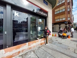 Una mujer salta un muro de ladrillo para poder acceder al cajero de la sucursal bancaria.