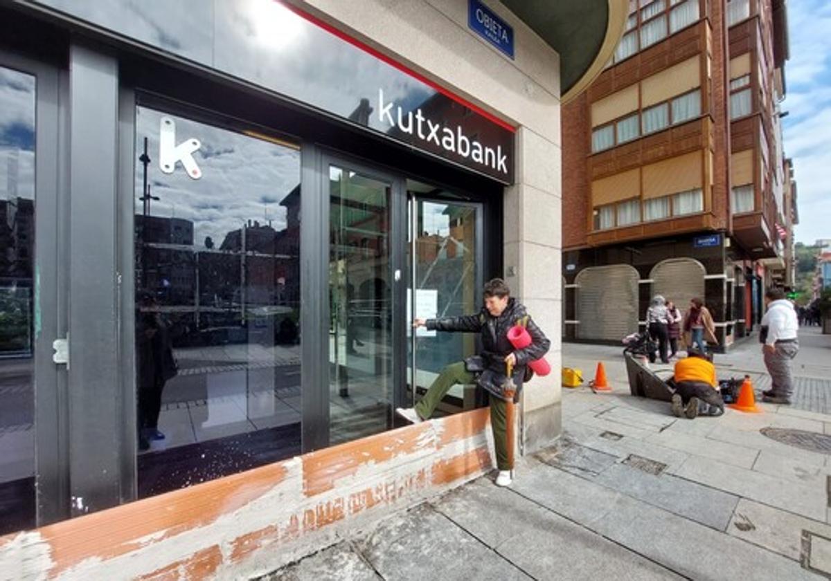 Una mujer salta un muro de ladrillo para poder acceder al cajero de la sucursal bancaria.