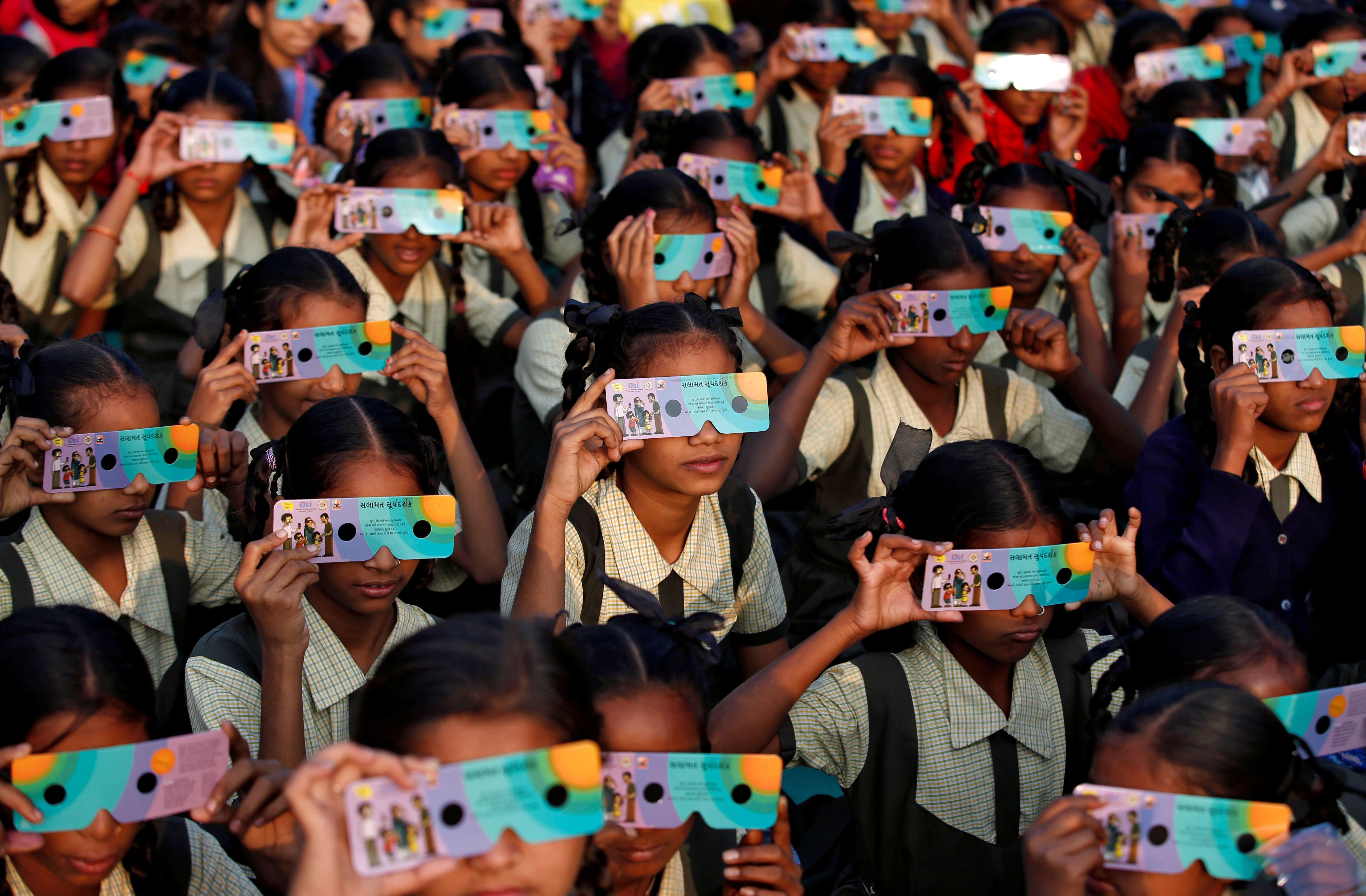 Escolares usan gafas para ver un eclipse en la India en 2019.