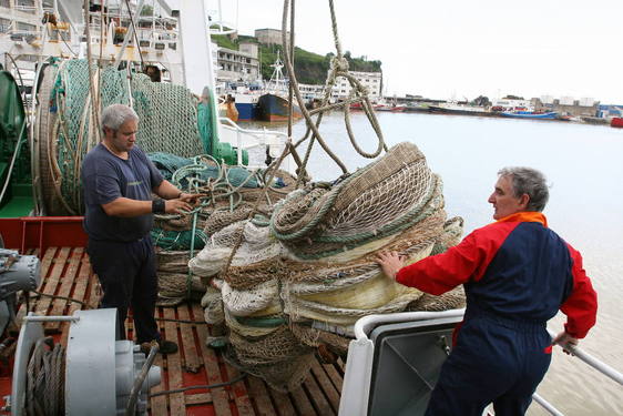 Dos arrantzales manipulan una red en un pesquero del puerto de Ondarroa.