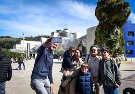 Un grupo de turistas se fotografía junto al Guggenheim.