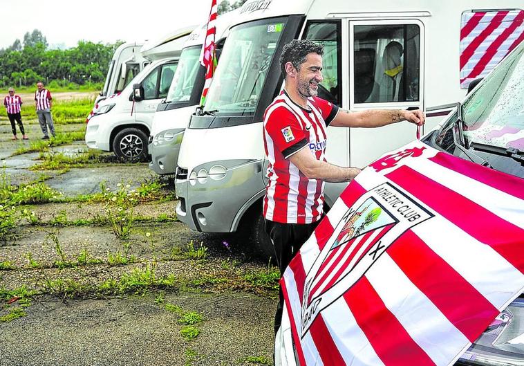 Las primeras autocaravanas ya están instaladas en la capital andaluza. En la imagen, el ermuarra Emilio Carral coloca una bandera rojiblanca en su vehículo.