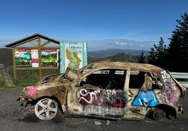 El vehículo abandonado está inmovilizado por un cepo y repleto de pintadas en plena puerta de entrada a Urdaibai.