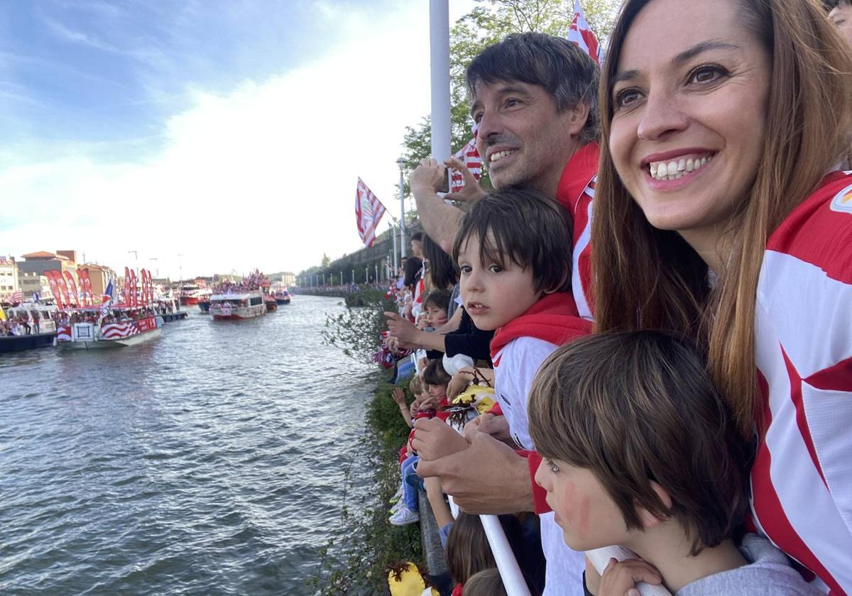 Alex e Iñigo observan junto a sus padres el paso de las decenas de embarcaciones que acompañaron a la gabarra.