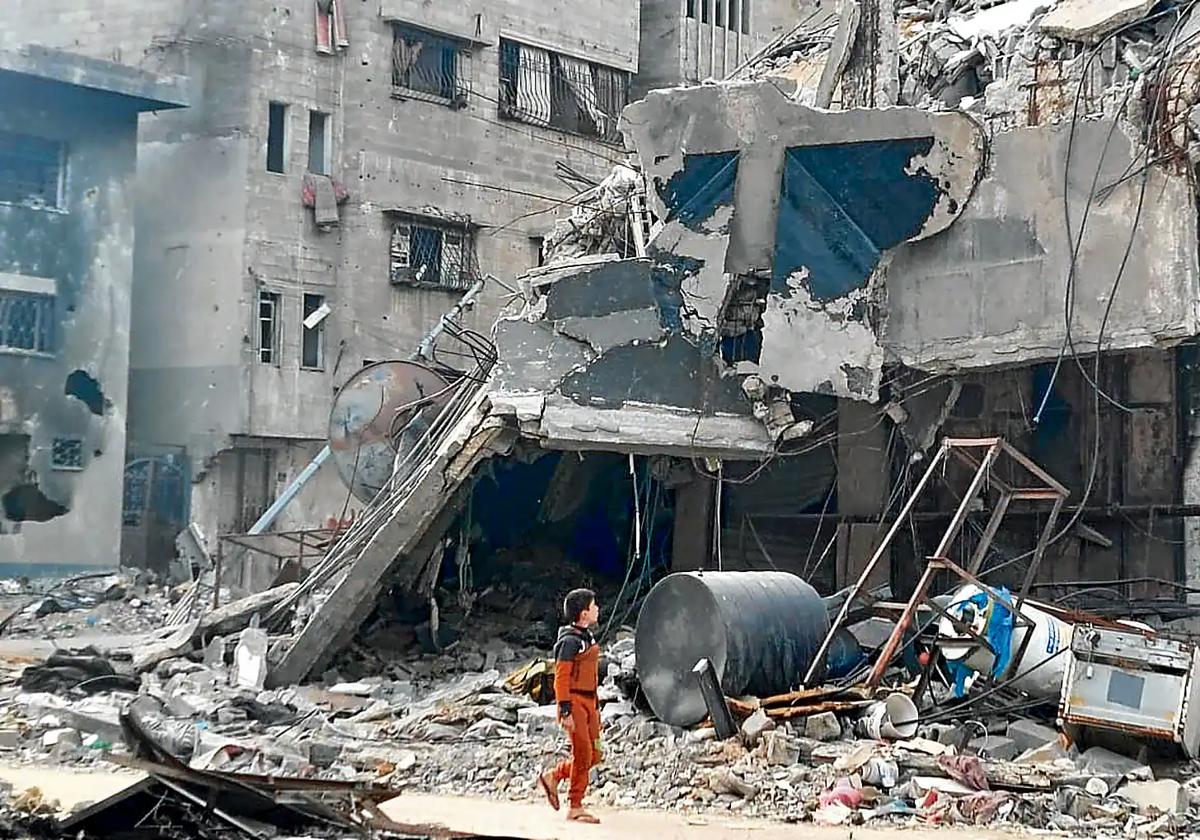 Un niño pasea junto a un edificio en ruinas en Gaza.