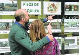 Una pareja consulta los precios del alquiler de viviendas en una inmobiliaria en el centro de Bilbao.