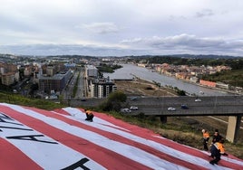 Momento en el que varios voluntarios de Protección Civil recogen la enseña, junto al puente de Rontegi.