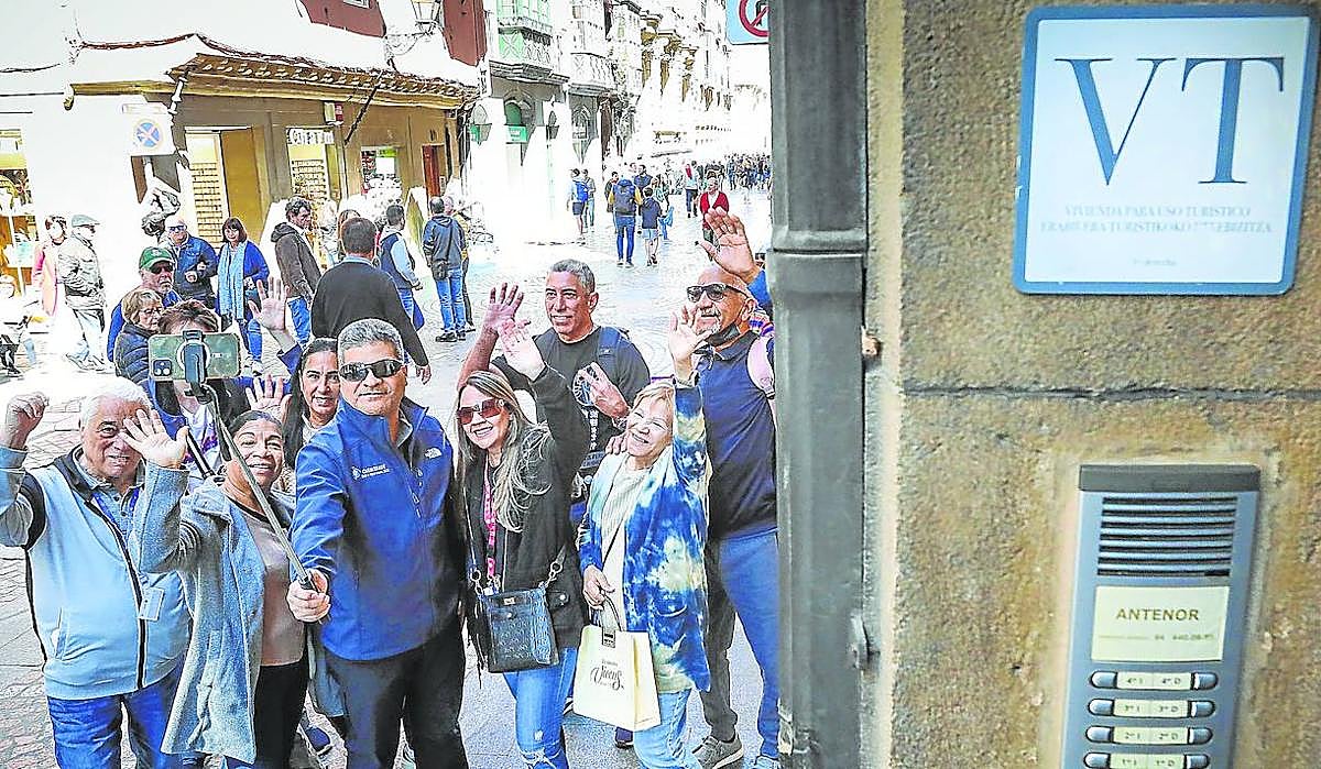Turistas de Puerto Rico se hacen un selfie junto al portal de una vivienda turística en el Casco Viejo de Bilbao.