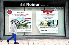 Una mujer pasa delante de una oficina de Neinor en Bilbao.